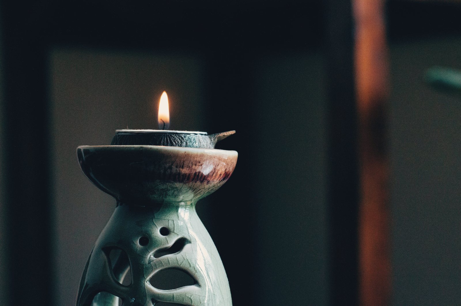 A candle burning in a ceramic holder