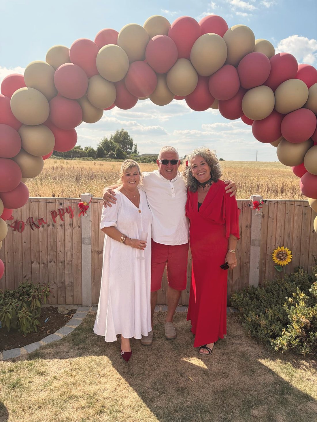 Leah with a couple beneath a balloon arch